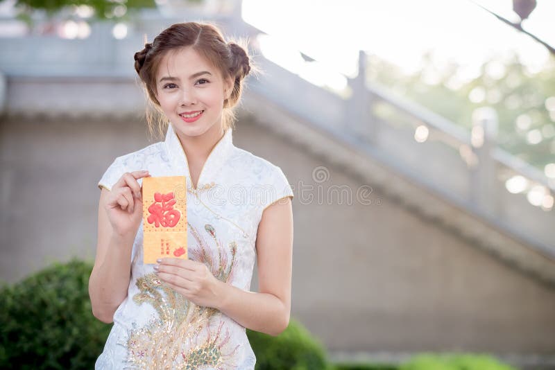 La femme asiatique dans le Chinois habillent juger le couplet 'heureux' (Chine images libres de droits La femme asiatique dans le Chinois habillent juger le couplet 'heureux' (Chine images libres de droits