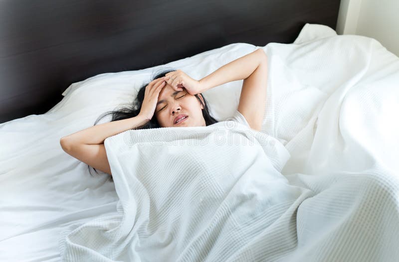 La femme asiatique font se réveiller un mal de tête sur le lit après pendant le matin photos libres de droits La femme asiatique font se réveiller un mal de tête sur le lit après pendant le matin photos libres de droits