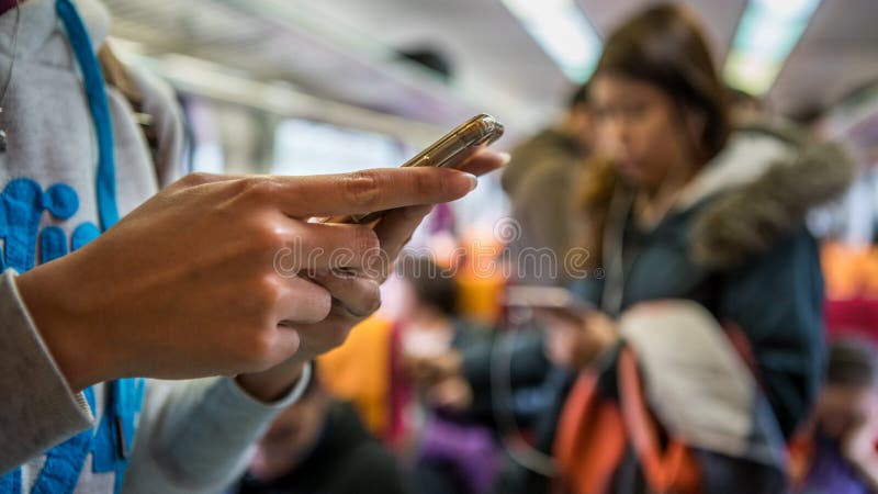 La femme asiatique se lèvent dans le train Utilisant le smartphone dans le souterrain image stock La femme asiatique se lèvent dans le train Utilisant le smartphone dans le souterrain image stock