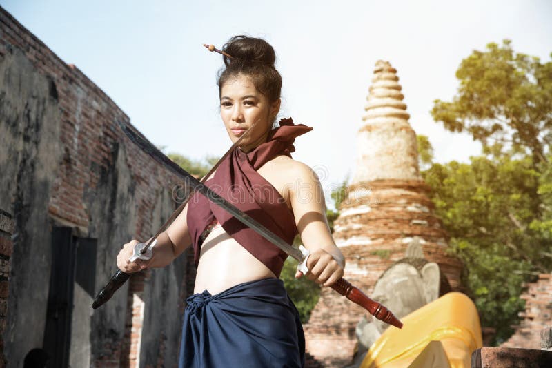 La femme assez asiatique posant dans les guerriers antiques thaïlandais s'habille photographie stock libre de droits