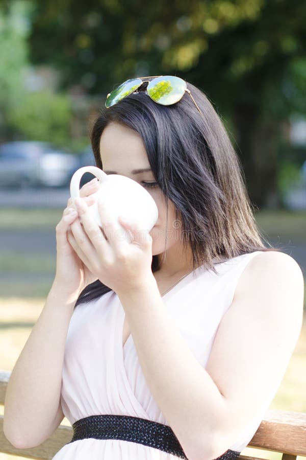 La femme avec la tasse de café en parc et le boivent photos stock La femme avec la tasse de café en parc et le boivent photos stock
