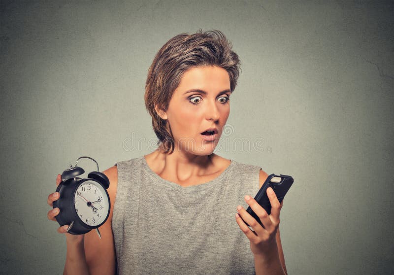 La femme avec le téléphone portable et le réveil a souligné le fonctionnement tard images libres de droits La femme avec le téléphone portable et le réveil a souligné le fonctionnement tard images libres de droits