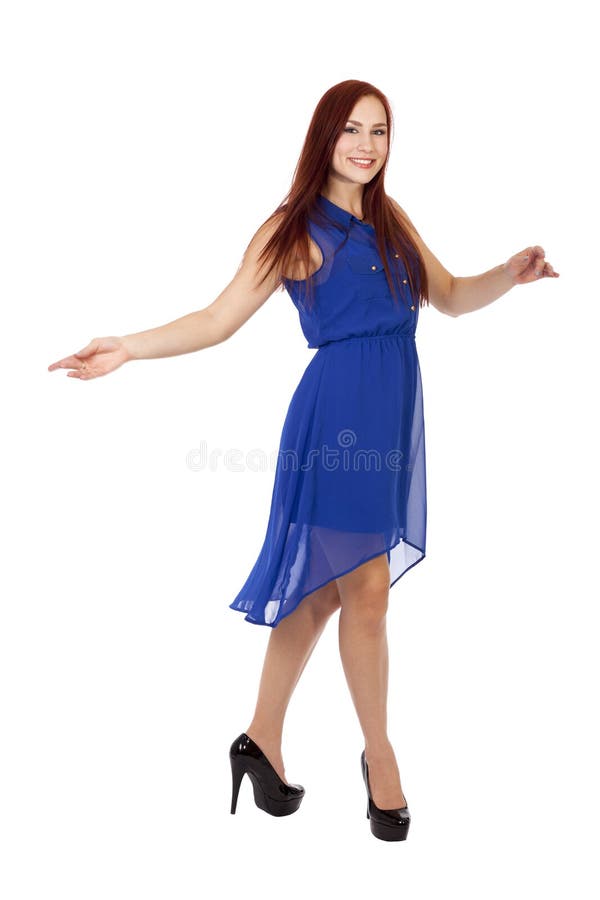 La femme avec les cheveux rouges danse dans sa robe bleue. image stock La femme avec les cheveux rouges danse dans sa robe bleue. image stock