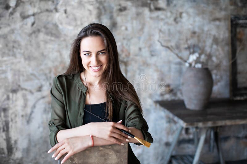 La femme avec une brosse dans sa main et un sourire avec du charme sur son visage a photographié la séance sur une chaise dans un images stock La femme avec une brosse dans sa main et un sourire avec du charme sur son visage a photographié la séance sur une chaise dans un images stock