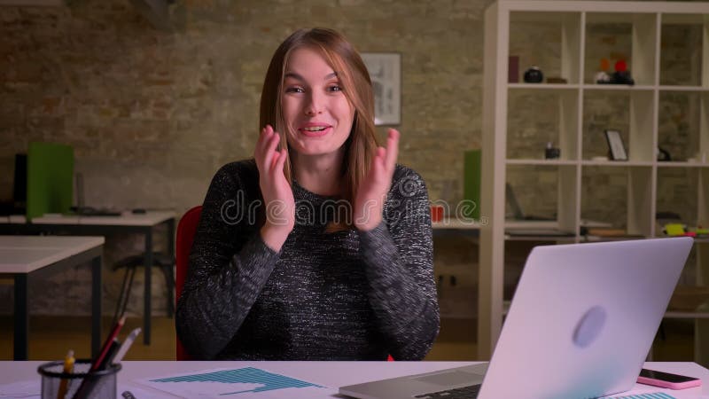 La femme caucasienne de gingembre s'asseyant dans le bureau observe le smth et devient extrêmement heureuse clips vidéos