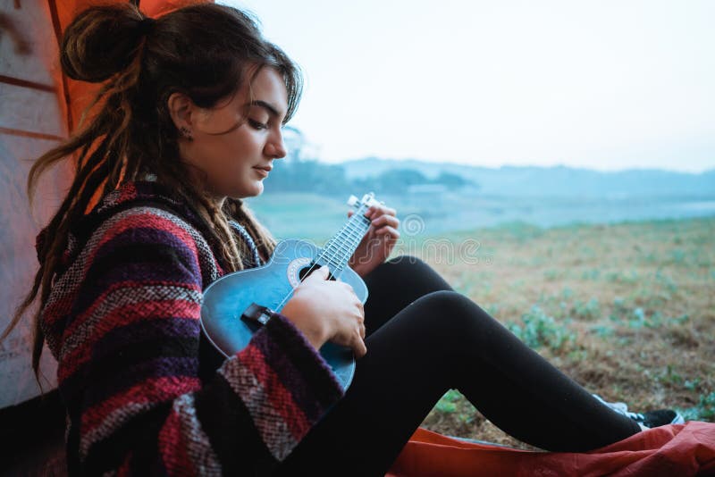 La femme caucasienne jouant la guitare après se réveillent photographie stock La femme caucasienne jouant la guitare après se réveillent photographie stock