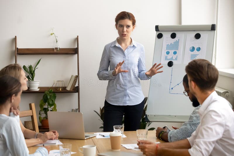 La femme d'affaires ambitieuse exp?riment?e pr?sente l'expos? lors de la r?union d'?quipe pr?s du flipchart photo libre de droits La femme d'affaires ambitieuse exp?riment?e pr?sente l'expos? lors de la r?union d'?quipe pr?s du flipchart photo libre de droits