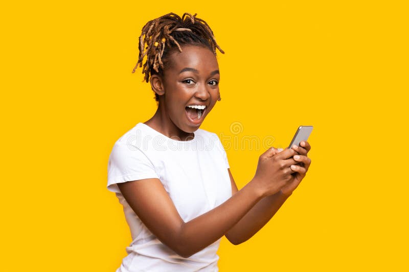 La femme de couleur excitée à l'aide du téléphone portable a obtenu le nouvel appli sympa