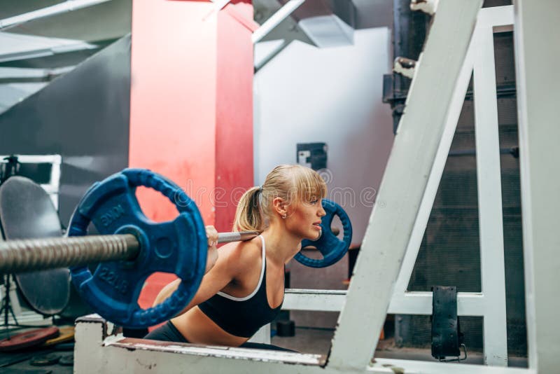La femme de forme physique faisant le barbell s'accroupit dans un gymnase image libre de droits La femme de forme physique faisant le barbell s'accroupit dans un gymnase image libre de droits