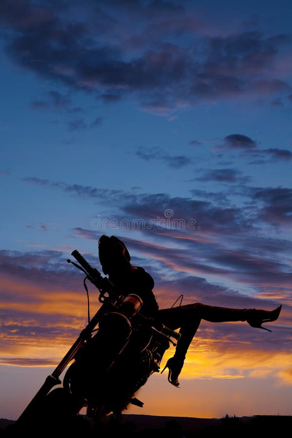 La femme de silhouette sur la jambe de moto dirigent l'arrière photos stock La femme de silhouette sur la jambe de moto dirigent l'arrière photos stock