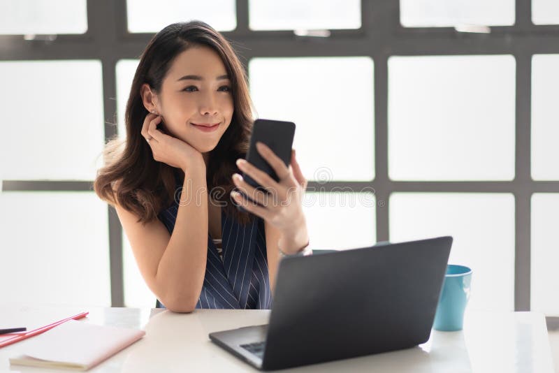 La femme de sourire d'affaires est tenante et regardante son smartphone images stock La femme de sourire d'affaires est tenante et regardante son smartphone images stock