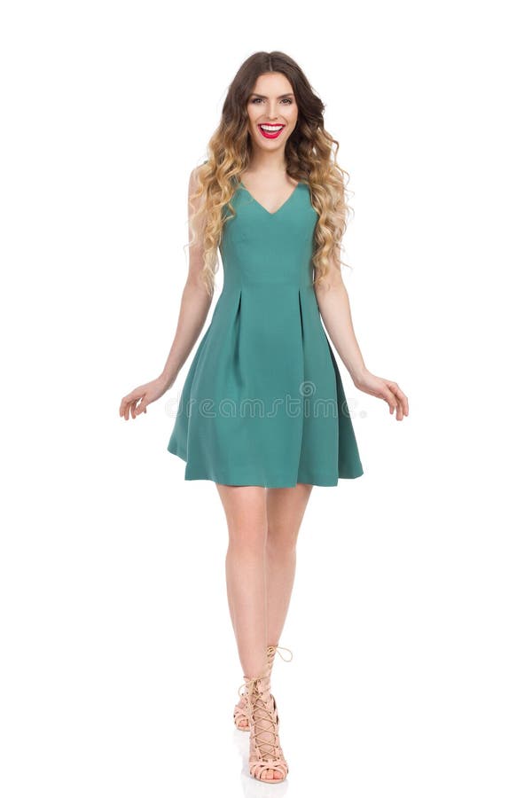 La femme de sourire dans la robe verte marche vers l'appareil-photo photo stock La femme de sourire dans la robe verte marche vers l'appareil-photo photo stock