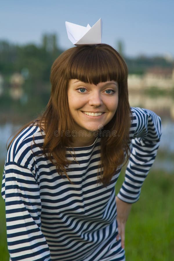 La femme a dedans dépouillé t-court avec le bateau de papier sur sa tête photos stock La femme a dedans dépouillé t-court avec le bateau de papier sur sa tête photos stock