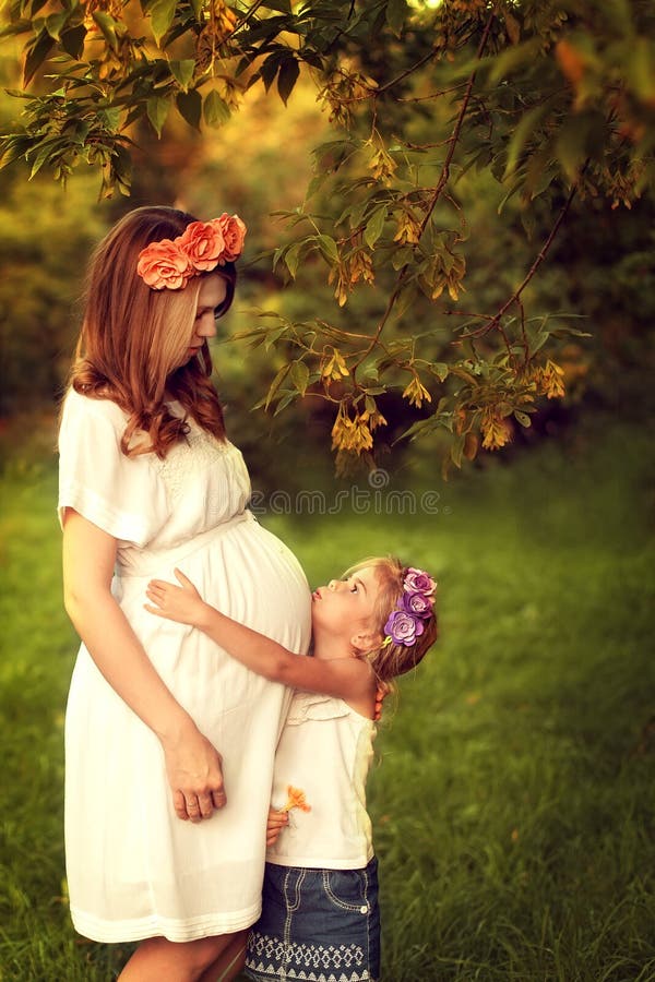 La femme enceinte de jeunes marche avec sa fille Étreindre de fille leur images libres de droits La femme enceinte de jeunes marche avec sa fille Étreindre de fille leur images libres de droits