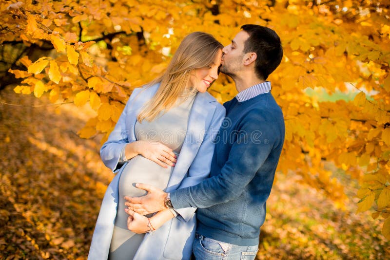La femme enceinte et l'homme posant à l'automne se garent photographie stock libre de droits La femme enceinte et l'homme posant à l'automne se garent photographie stock libre de droits