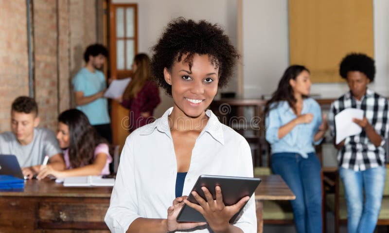 La femme encourageante d'afro-américain avec le comprimé à commencent le bureau photographie stock La femme encourageante d'afro-américain avec le comprimé à commencent le bureau photographie stock