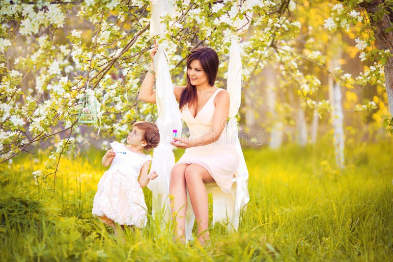 La femme et l'enfant heureux pendant le ressort de floraison font du jardinage. Jour de mères photos libres de droits La femme et l'enfant heureux pendant le ressort de floraison font du jardinage. Jour de mères photos libres de droits