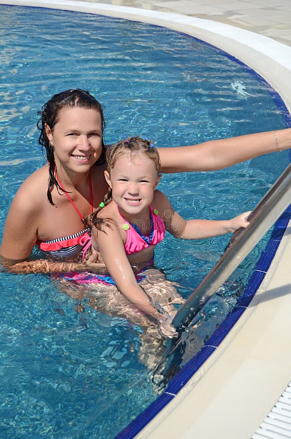 La femme et sa petite fille mignonne ont un amusement dans la piscine photographie stock libre de droits La femme et sa petite fille mignonne ont un amusement dans la piscine photographie stock libre de droits