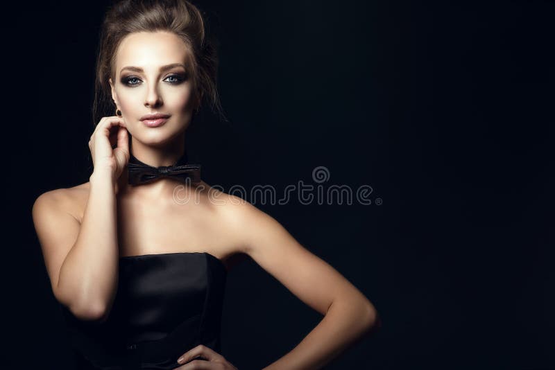 La femme fascinante magnifique avec beau composent et les cheveux d'updo portant la robe et le noeud papillon noirs de corset sur photo libre de droits La femme fascinante magnifique avec beau composent et les cheveux d'updo portant la robe et le noeud papillon noirs de corset sur photo libre de droits