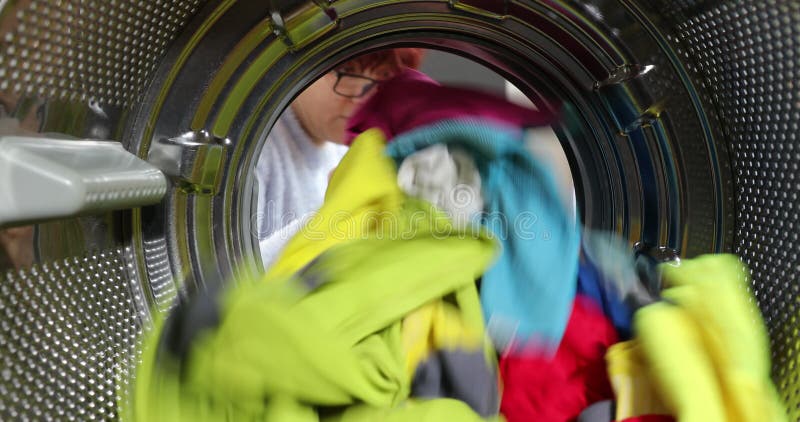 La femme fatiguée sort les vêtements de la machine à laver. assis sur la buanderie. vue sur le linge intérieur banque de vidéos