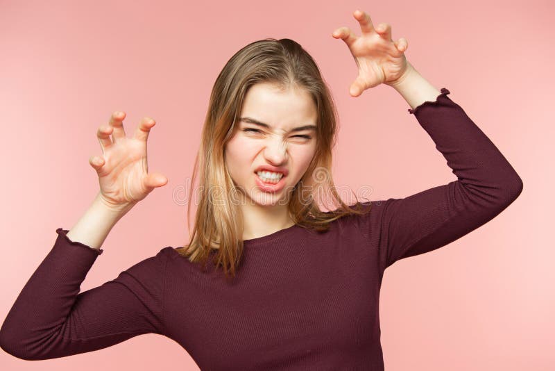 La femme fâchée, espiègle et d'alertes teaseing sur le fond rose de studio et regarde l'appareil-photo images stock La femme fâchée, espiègle et d'alertes teaseing sur le fond rose de studio et regarde l'appareil-photo images stock