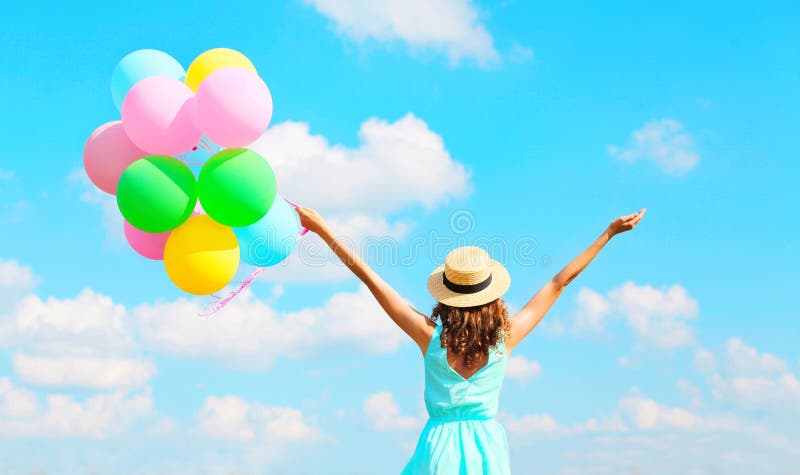 La femme heureuse de vue arrière avec les ballons colorés d'un air apprécie un jour d'été sur le fond de ciel bleu photo libre de droits La femme heureuse de vue arrière avec les ballons colorés d'un air apprécie un jour d'été sur le fond de ciel bleu photo libre de droits