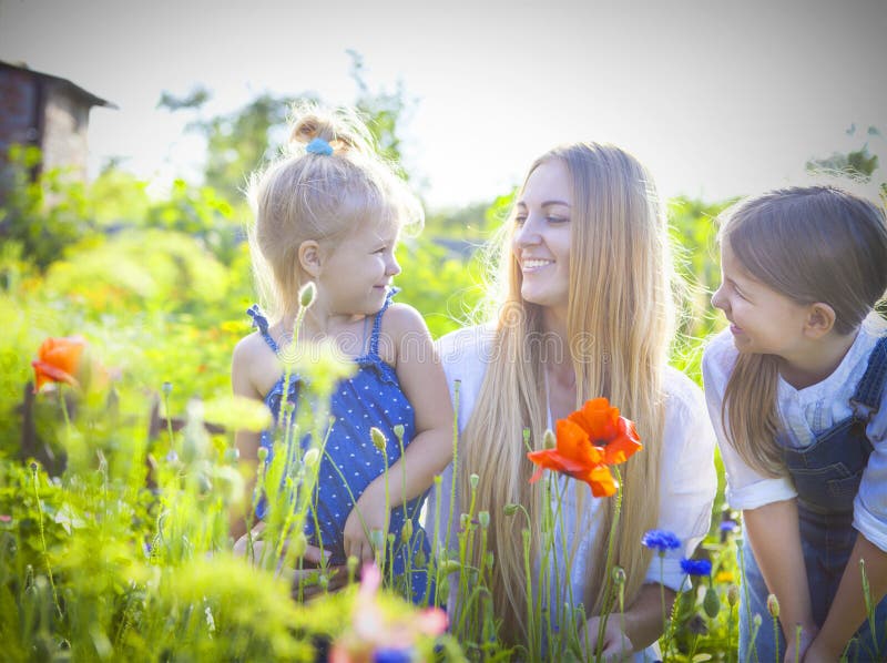 La femme heureuse et ses filles pendant le ressort de floraison font du jardinage photo stock La femme heureuse et ses filles pendant le ressort de floraison font du jardinage photo stock