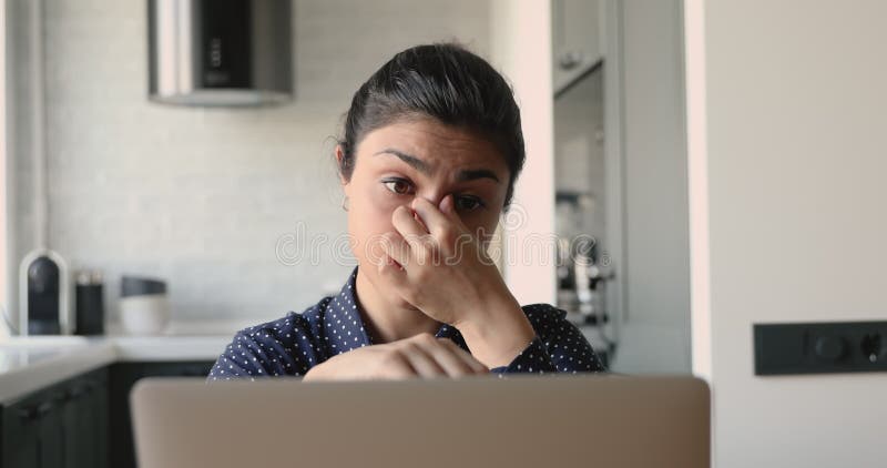 La femme indienne fatiguée supprime des lunettes siègent du travail d'ordinateur