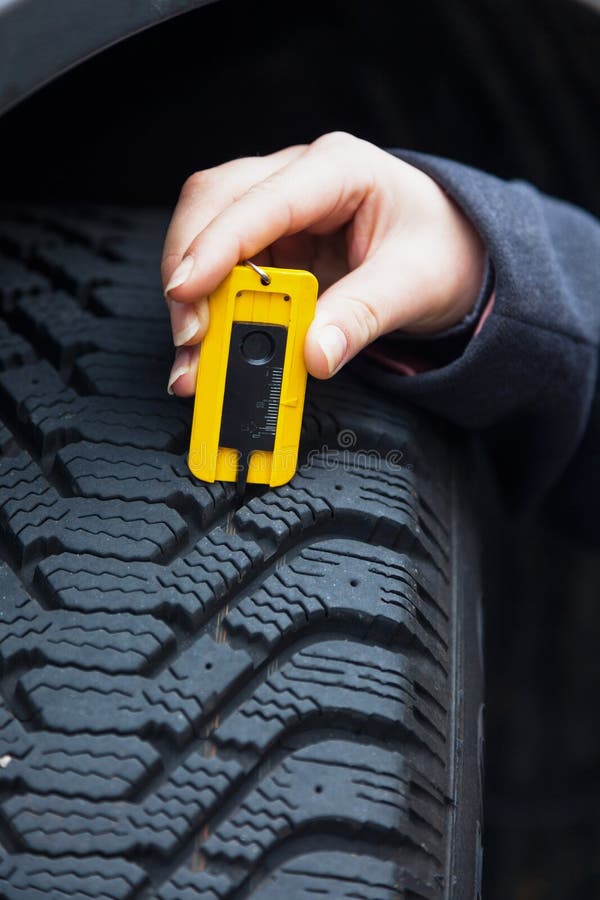 La Femme Mesure La Bande De Roulement De Pneu D'un Pneu De Voiture Photo  stock - Image du jauge, profil: 31345576