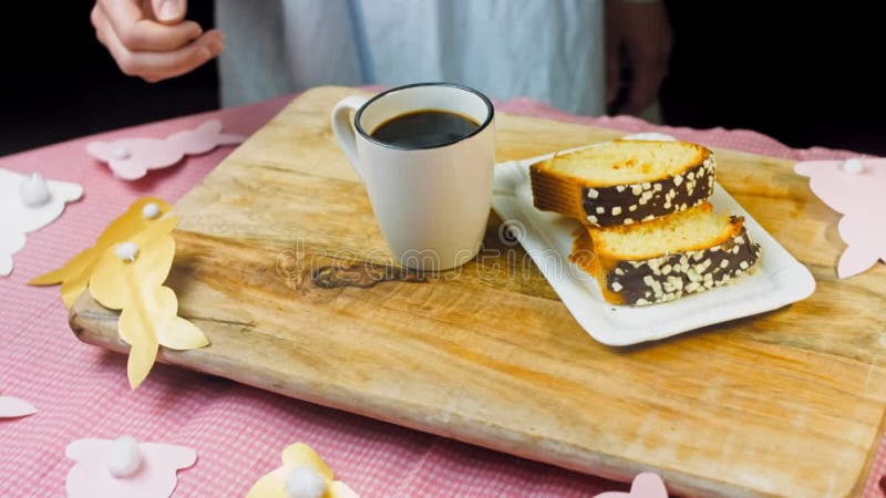 La femme met une tasse de café sur la table où il y a un gâteau au chocolat. sur le fond sont purges de pâques faites banque de vidéos