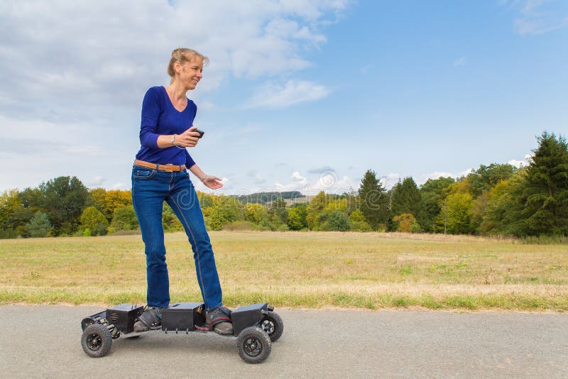 La femme néerlandaise conduit le mountainboard électrique en nature photographie stock libre de droits La femme néerlandaise conduit le mountainboard électrique en nature photographie stock libre de droits