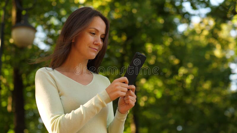 La femme ont plaisir à l'aide du smartphone, lisant de l'écran de téléphone