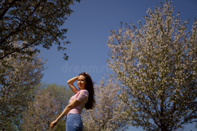 La femme r?ussie d'affaires appr?cie son temps libre de loisirs en parc avec les cerisiers de floraison de Sakura utilisant des j photographie stock libre de droits La femme r?ussie d'affaires appr?cie son temps libre de loisirs en parc avec les cerisiers de floraison de Sakura utilisant des j photographie stock libre de droits