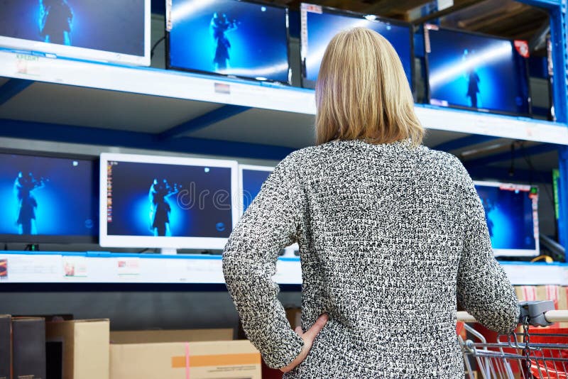 La femme regarde l'affichage à cristaux liquides TV dans la boutique photo stock La femme regarde l'affichage à cristaux liquides TV dans la boutique photo stock