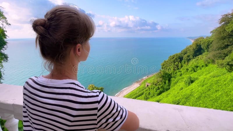La femme regarde les arbres noirs vert mer et le ciel bleu nuageux banque de vidéos