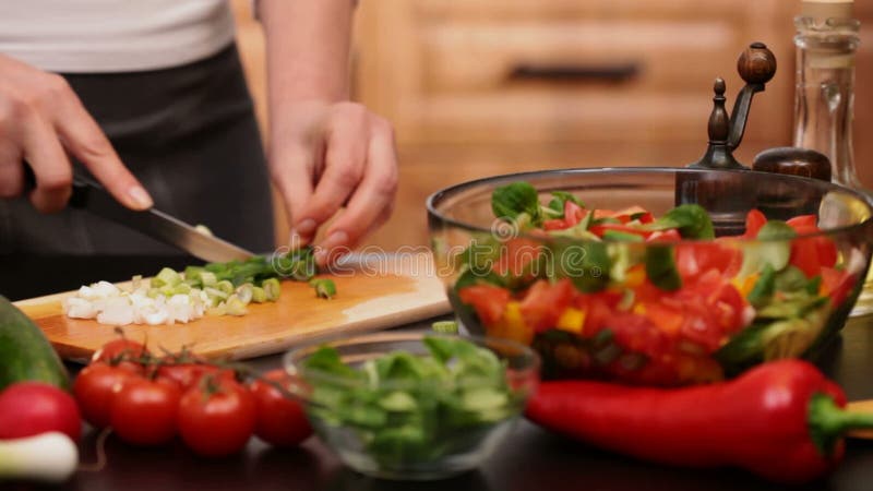 La femme remet couper des oignons de ressort pour une salade de légumes clips vidéos