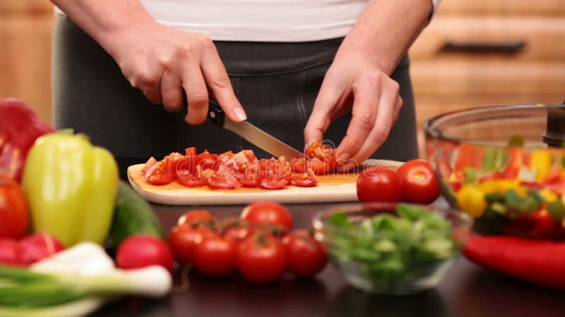 La femme remet couper en tranches des tomates-cerises pour une salade de légumes clips vidéos