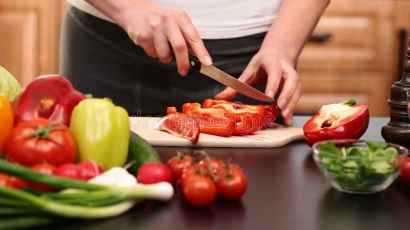 La femme remet couper en tranches le paprika rouge pour une salade de légumes clips vidéos