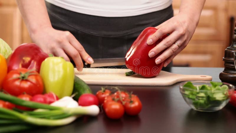 La femme remet couper le paprika rouge pour une salade de légumes banque de vidéos