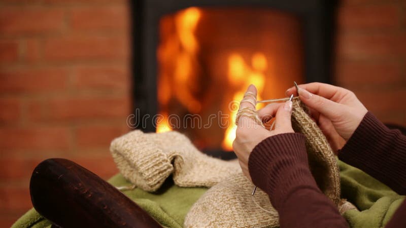 La femme remet les chaussettes de tricotage de laine par le feu banque de vidéos