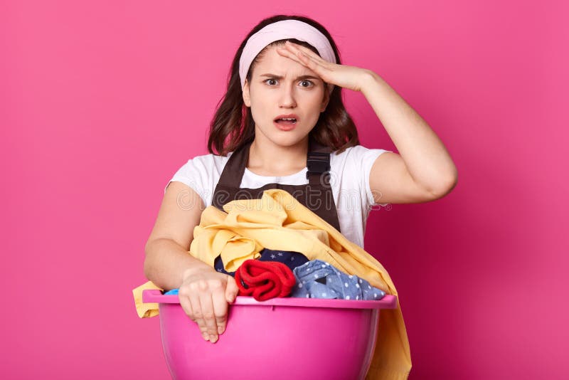 La femme rentre le bassin rose énorme de mains avec les vêtements sales, couvertures, serviettes et l'autre textile à la maison, images stock La femme rentre le bassin rose énorme de mains avec les vêtements sales, couvertures, serviettes et l'autre textile à la maison, images stock