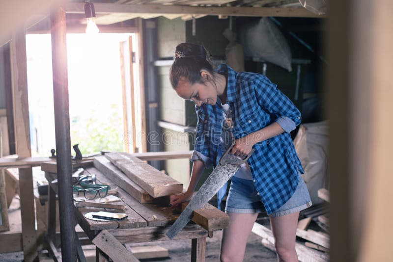 La femme s'est engagée en traitant le bois dans l'atelier à la maison, menuiserie