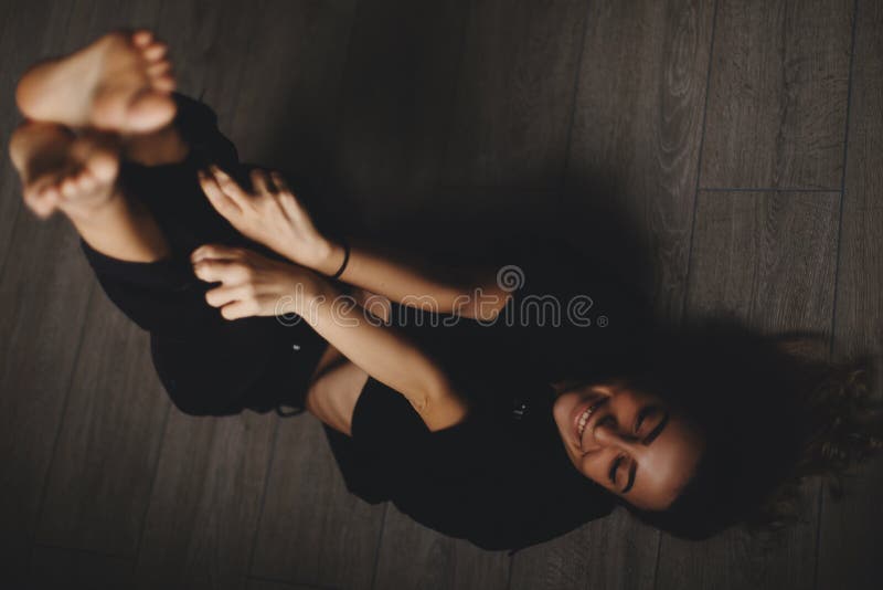 La femme sexy attirante se trouve sur le plancher La fille semble heureuse et des sourires Femme se trouvant sur le plancher avec photos stock La femme sexy attirante se trouve sur le plancher La fille semble heureuse et des sourires Femme se trouvant sur le plancher avec photos stock