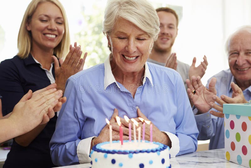 La femme supérieure souffle des bougies de gâteau d'anniversaire à la partie de famille images stock La femme supérieure souffle des bougies de gâteau d'anniversaire à la partie de famille images stock