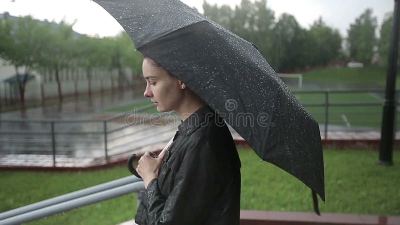 La femme triste seule descend la rue sous la forte pluie Mouvement lent