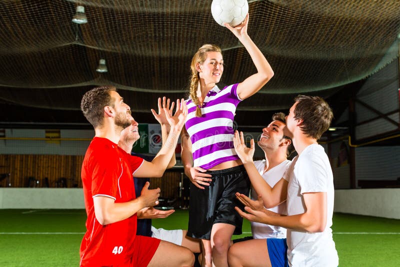 La femme a un football à disposition, des hommes se mettant à genoux vers le bas photos libres de droits
