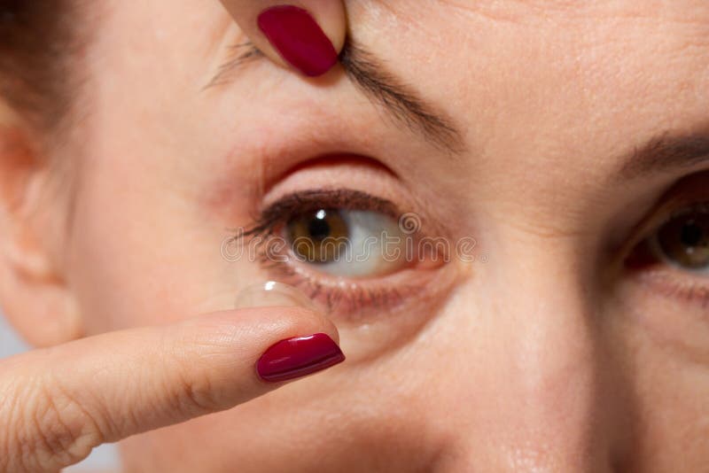 La femme âgée par milieu avec des poches sous les yeux mettant le verre de contact dans son oeil brun, se ferment et macro vue Mé photographie stock libre de droits La femme âgée par milieu avec des poches sous les yeux mettant le verre de contact dans son oeil brun, se ferment et macro vue Mé photographie stock libre de droits