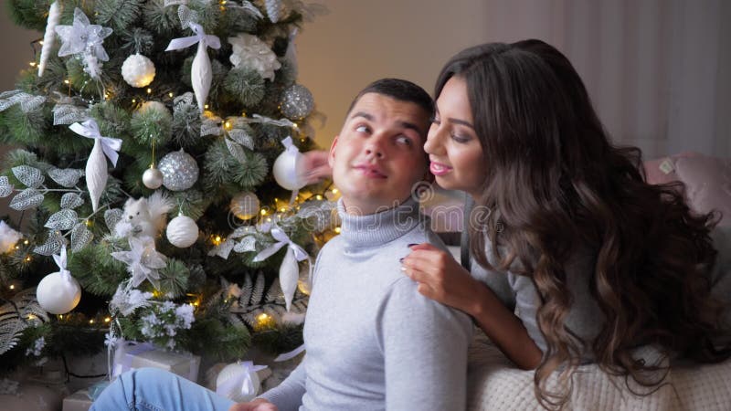 La femme étreint doucement son homme à la maison, des moments romantiques la veille de la nouvelle année