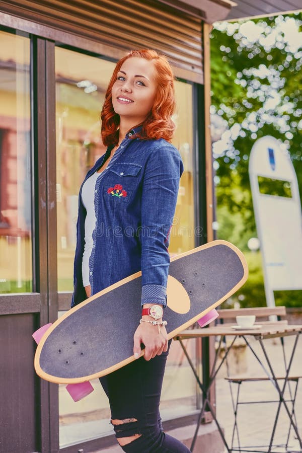 La femmina attraente della testarossa tiene Longboard fotografia stock