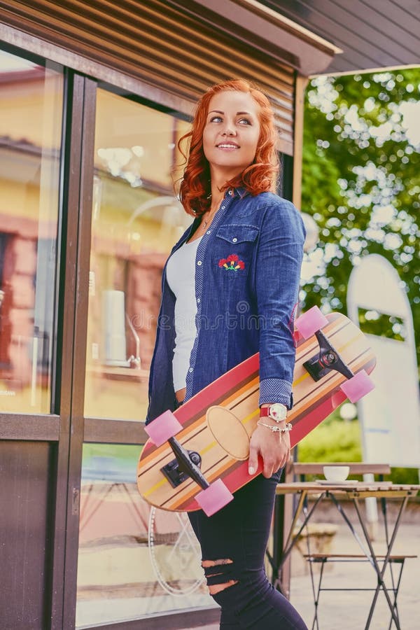 La femmina attraente della testarossa tiene Longboard immagini stock